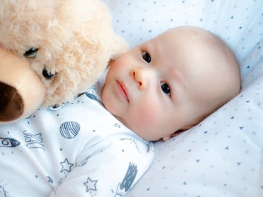 Sevimli 3 aylık karışık ırk Asya Kafkas çocuk mutlu gülümseyerek görünümlü ve kameraya gülüyor, sağlıklı çocuk erkek bebek. Onun oyuncak ayı ile Yarım Tay yarı Lehçe.