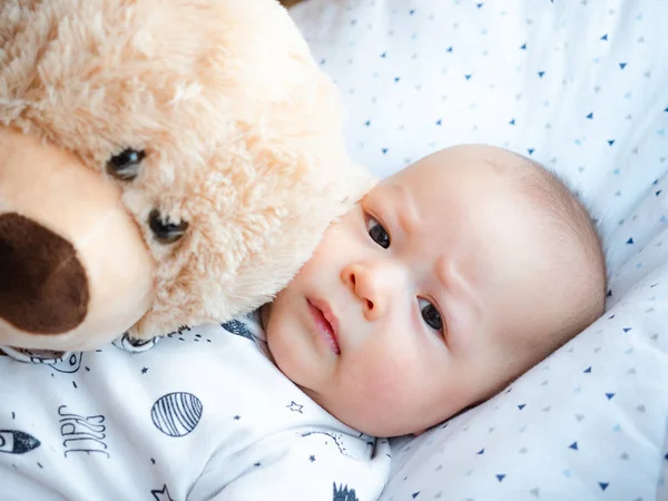 Cute 3 months old old mixed race Asian Caucasian boy looking happy smiling and laughing at the camera, healthy child baby boy. Half Thai half Polish with his teddy bear.