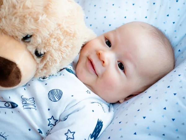 Cute 3 months old old mixed race Asian Caucasian boy looking happy smiling and laughing at the camera, healthy child baby boy. Half Thai half Polish with his teddy bear.