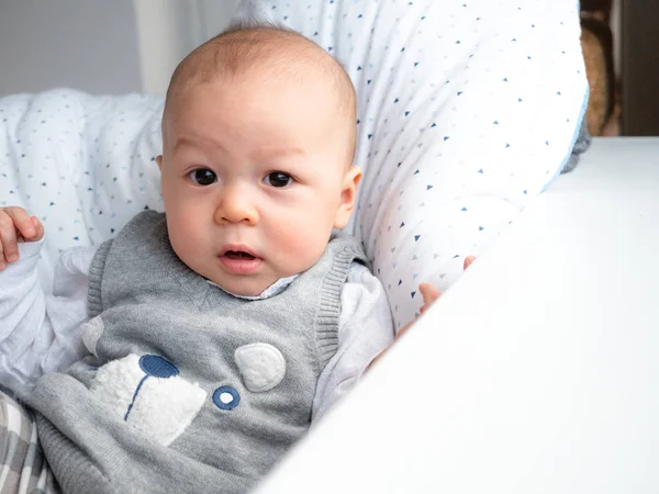 Cute 4 months old mixed half race Asian Caucasian boy looking happy smiling and laughing at the camera, healthy child baby boy. Half Thai half Polish. Winter, elegance cloth sitting next to window