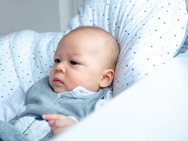 Cute 4 months old mixed half race Asian Caucasian boy looking happy smiling and laughing at the camera, healthy child baby boy. Half Thai half Polish. Winter, elegance cloth sitting next to window