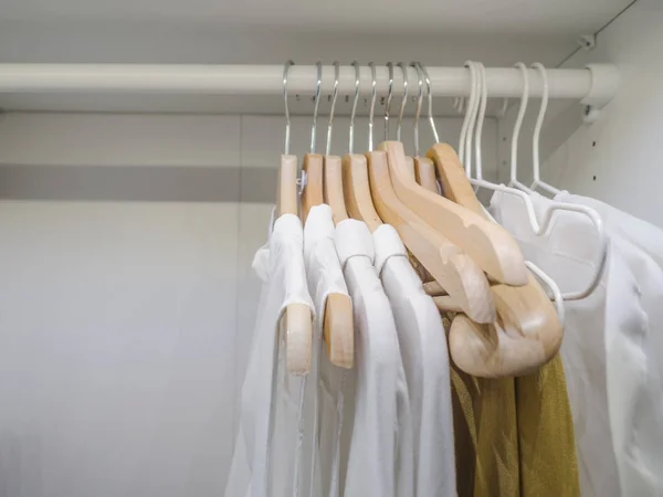 white shirts hanging in a row - closeup shot of a classic white shirt in a modern wardrobe.