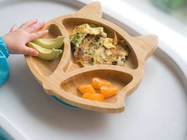Bebek eller tarafından yeme, Bebek BLW yöntemi ile organik biyo sebze yeme, Bebek weaning açtı. Mutlu Vejetaryen çocuk. Toddler kendini yiyor, kendini besliyor. Bebek bebeği yiyor. Portakal, avokado ile omlet