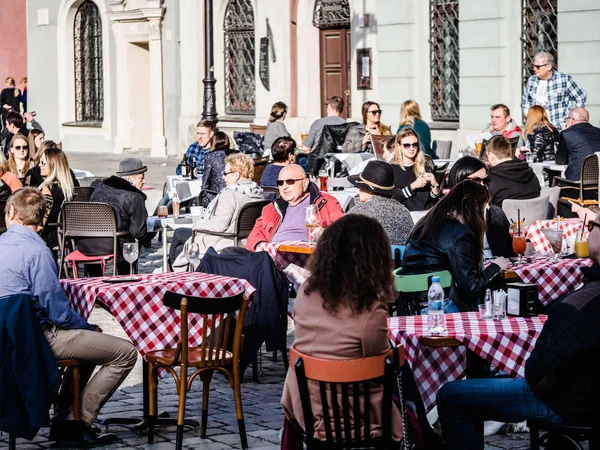 Poznan, Old town, Poland, 2 April 2018, People and old man relaxing, sitting and enjoy of good weather in the restaurant outdoor at the town, drinking beer. — Stock Photo, Image