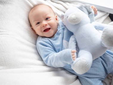 Oyuncak ayı ile mutlu bebek sevimli 6 ay eski karışık yarım yarış Asya Kafkas çocuk mutlu gülümseyen ve fotoğraf makinesi, sağlıklı çocuk Baby çocuk gülüyor bakıyor. Yarım Tay yarım Lehçe, mavi beyaz kavramı