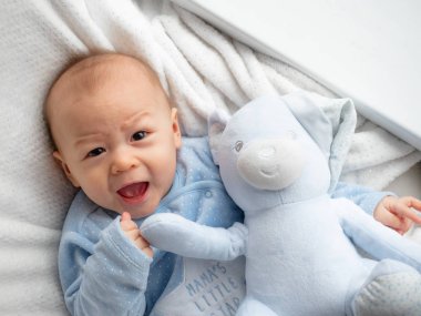 Oyuncak ayı ile mutlu bebek sevimli 6 ay eski karışık yarım yarış Asya Kafkas çocuk mutlu gülümseyen ve fotoğraf makinesi, sağlıklı çocuk Baby çocuk gülüyor bakıyor. Yarım Tay yarım Lehçe, mavi beyaz kavramı