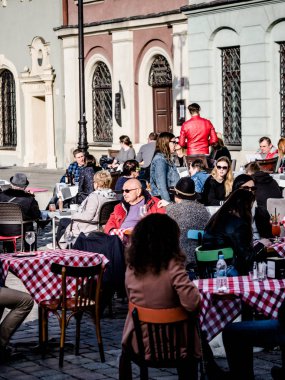 Poznan, eski kent, Polonya, 2 Nisan 2018, Insanlar ve yaşlı adam rahatlatıcı, oturma ve restoranda güzel hava keyfini şehirde, bira içme.
