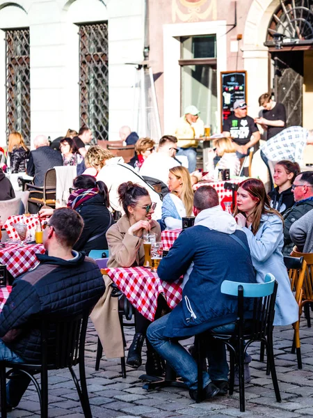 Poznan, Casco antiguo, Polonia, 2 de abril de 2018, Personas con paños de moda se sientan y disfruten del buen tiempo en el restaurante al aire libre en la ciudad, bebiendo cerveza . — Foto de Stock