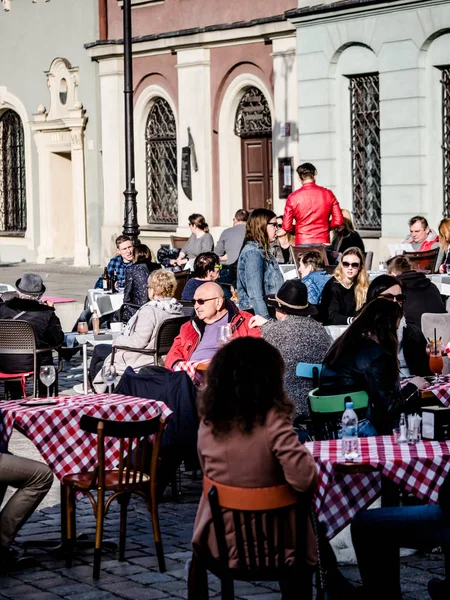 Poznan, Casco antiguo, Polonia, 2 de abril de 2018, Personas y anciano relajarse, sentarse y disfrutar del buen tiempo en el restaurante al aire libre en la ciudad, beber cerveza . — Foto de Stock