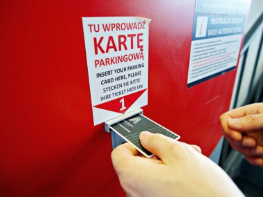 Alışveriş merkezinde Park ödemek için makineye bilet kartı ekleyerek bir adam, Poznan, Polonya, 13 Temmuz 2018