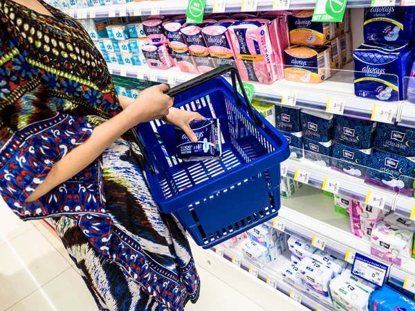 Young woman hands holding  Intimate brand of sanitary napkins, sanitary pad for women menstruation period compare quality in the supermarket with blurred products, Poznan, Poland, 4 Feb 2018 — Stock Photo, Image