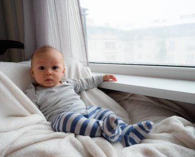 Sevimli yakışıklı 5 ay eski yarım yarış Asya beyaz çocuk mutlu gülümseyerek ve kameraya, gülen sağlıklı çocuk bebek çocuk arıyorsunuz karışık. Yarım Tay yarım Lehçe bebek önlük giymek.