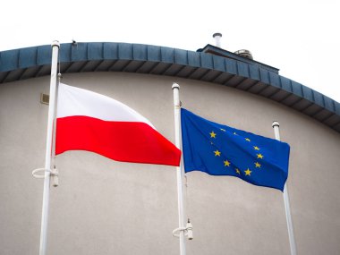 Polonya ve Avrupa Birliği bayrakları, uçan ve arka plan beyaz duvar ofis ile sallayarak.