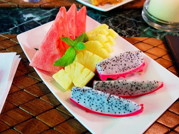 Surtido de frutas tropicales en un plato blanco, piña, fruta de dragón y sandía servidas en el restaurante — Foto de Stock