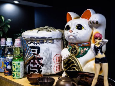 Maneki-neko kedi. Elle çizilmiş şanslı beyaz kedi oturuyor. Japon kültürü, katalizatörler Retro Japon kültürel koleksiyonu Japon restoranında, 13 Temmuz 2018, Poznan, Polonya