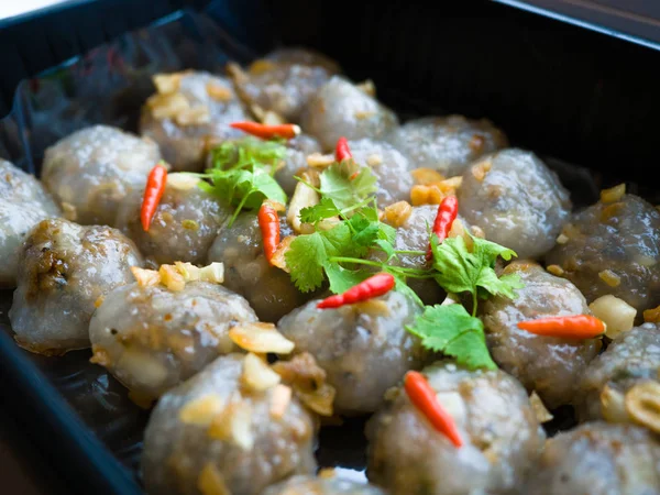 Aperitivo tailandês, bolas de tapioca cozidas no vapor com recheio de amendoim e carne de porco com pimenta, coentro e alho em uma caixa de bandeja de plástico preto para levar para casa . — Fotografia de Stock