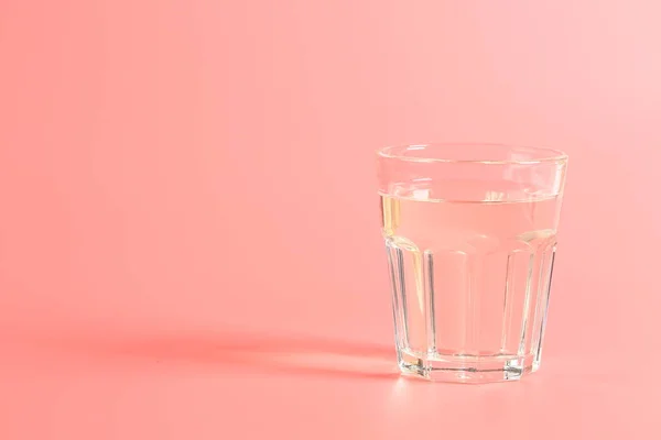 Szklanka wody na różowym tle. — Zdjęcie stockowe