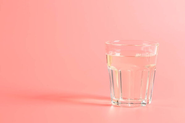 glass of water on a pink background.