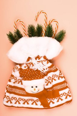 Pembe Noel arkaplanı. Hediyeli kırmızı çanta. Lolipoplar. Firavun dalları.