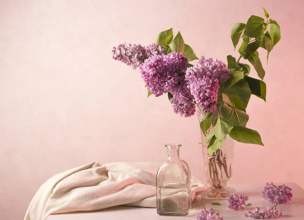 still life with a lilac in a glass bottle