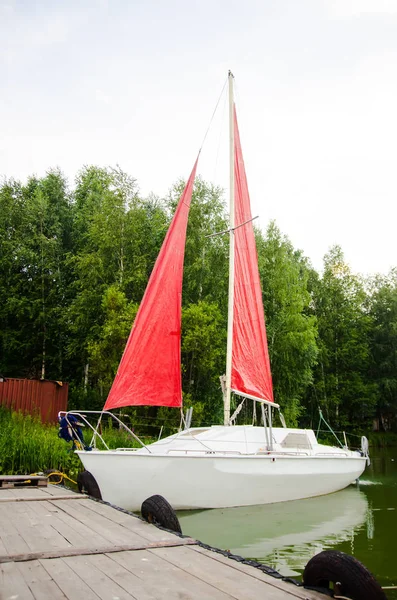 Kırmızı yelkenli demirli beyaz yat