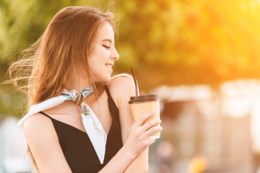 Mutlu genç kadın bankta kahve içiyor