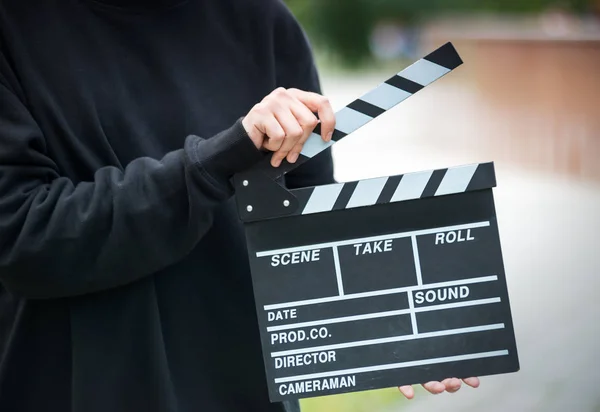 A man with clapperboard outdoor. Cinema production