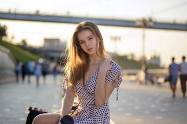 elinde kahve ile güzel kız sokakta bir bankta oturur