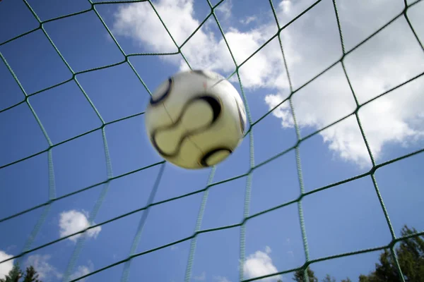 Ball inside football gate against blue clear sky