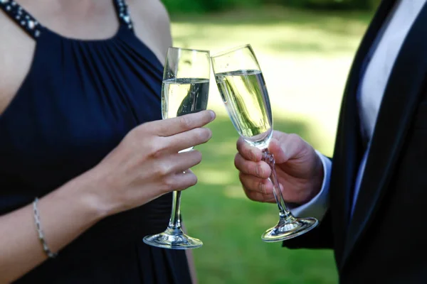 Married couple celebrating wedding and clinking by champagne glasses