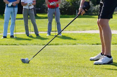 Kısmi görünümü adamın arkasında bekleyen diğer oyuncular ise golf kulübü tarafından topa vurmak hazırlanıyor