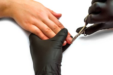 Manikürcü kız tırnaklarına manikür yapıyor. Siyah eldivenlerle tırnak törpülüyor. çivi ve ellere dikkat et. Beyaz bir arkaplanda