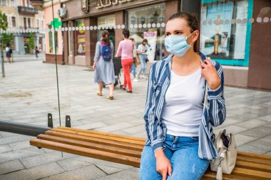 Otobüs durağındaki tıbbi maskeli kız. Koronavirüse karşı koruma.