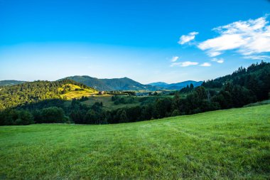 Dağ tepeleri ve ormanların arka planındaki dağ vadisi. Mavi gökyüzü. Doğada sabah.