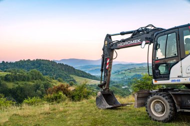 Volovetler, Ukrayna - 08 / 27 / 2020: Dağlar ve ormanların arka planında saklanan 140w kazıcı.