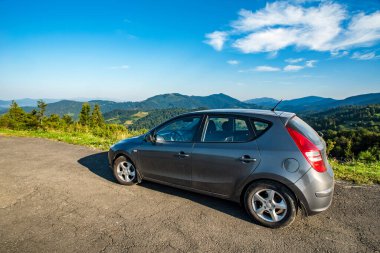 SEVGİLER, UKRAINE - 7 Eylül. 2020: Hyundai arabası ve 30 hatchback dağlardaki bir kır yolunda. Yazın gün doğumunda güzel ulaşım manzarası. 