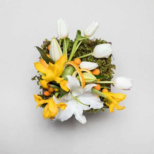 Flower arrangement. Original bouquet of flowers and greens isolated on soft gray background.High quality photo.