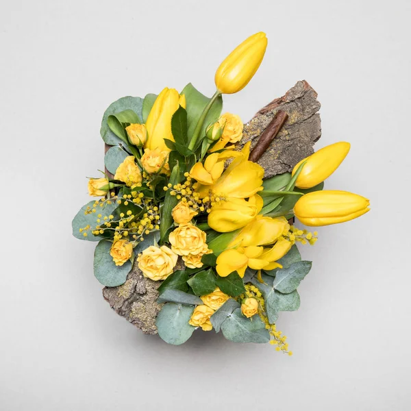 Flower arrangement. Original bouquet of flowers and greens isolated on soft gray background.High quality photo.