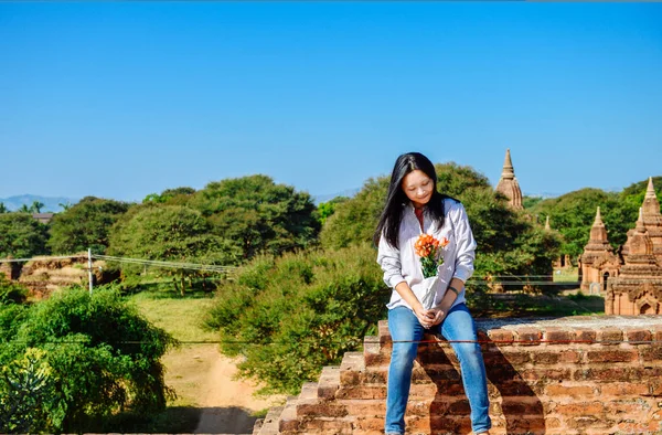 Kız rosees elinde pagoda Bagan, Myanmar adlı kenarında otururken görünüyor