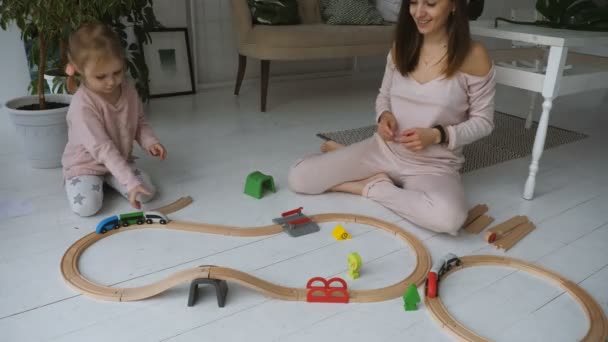 Madre y su pequeña hija juegan con el ferrocarril de madera — Vídeos de Stock