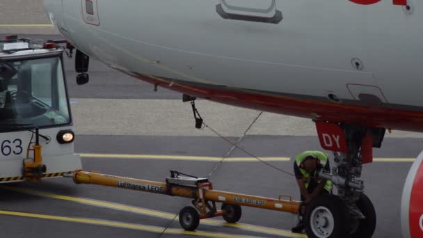 Un employé de l'aéroport sort la barre de remorquage de l'avion — Video
