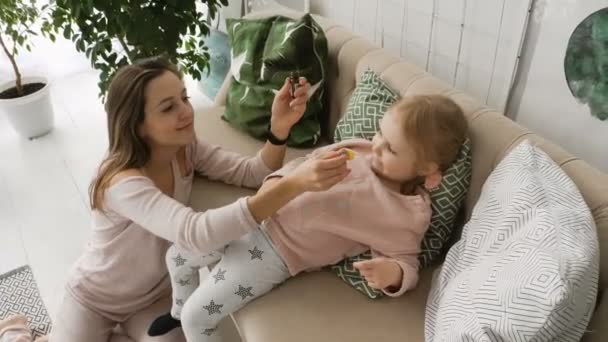 Мать капает лекарства в нос дочерей — стоковое видео
