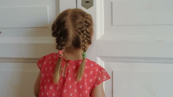 Маленькая девочка заглядывает в дверь — стоковое видео
