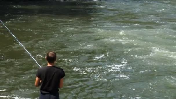 Homem está pescando junto ao rio — Vídeo de Stock