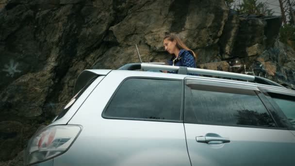 Женщина-фрилнасер работает с ноутбуком на крыше своей машины — стоковое видео