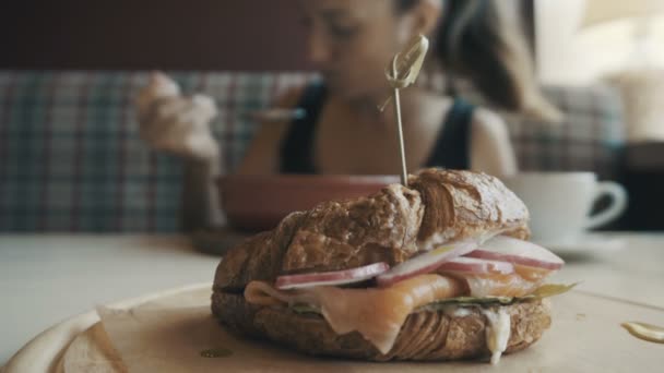Ontbijt. Jonge vrouw is eten in café — Stockvideo