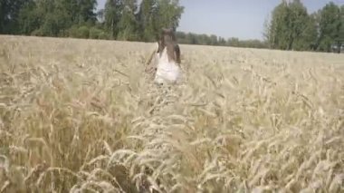 Genç kadın bir buğday alanında bir bisiklet ile gidiyor