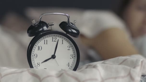 Молода жінка прокидається від будильника — стокове відео