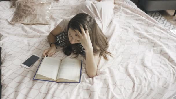 Brunette lying on the bed and reading — Stock Video