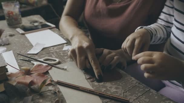 Bir çocuk ile anne yapmak bir el yapımı kağıt ve yaprakları — Stok video